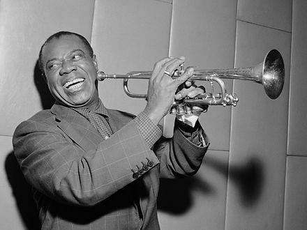 Louis Armstrong, holding a trumpet and smiling